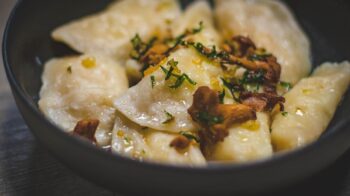 Appetizing pierogi with chanterelle mushrooms and herbs, captured indoors for a gourmet presentation. - Photo by Valeria Boltneva on Pexels