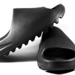 Close-up of black slide sandals on a white surface, showcasing modern minimalist design. - Photo by Terrance Barksdale on Pexels