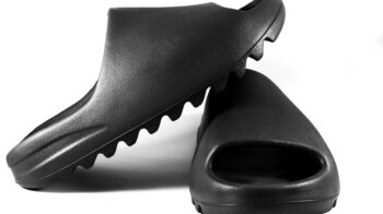 Close-up of black slide sandals on a white surface, showcasing modern minimalist design. - Photo by Terrance Barksdale on Pexels