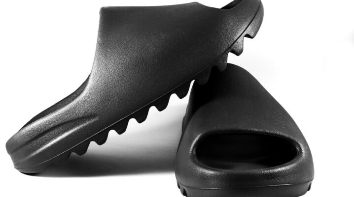 Close-up of black slide sandals on a white surface, showcasing modern minimalist design. - Photo by Terrance Barksdale on Pexels