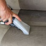 Hands using a vacuum nozzle to deeply clean a fabric car seat, removing dirt and stains. - Photo by Khunkorn Laowisit on Pexels