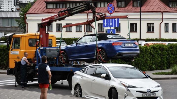 Towing a blue Audi convertible in a bustling city street. - Photo by Artem Makarov on Pexels
