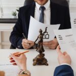 Legal professionals reviewing divorce documents in a law office with a Lady Justice statue. - Photo by https://kaboompics.com/ on Pexels