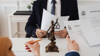 Legal professionals reviewing divorce documents in a law office with a Lady Justice statue. - Photo by https://kaboompics.com/ on Pexels